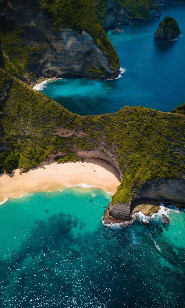 An aerial shot of the ocean surrounded by beautiful cliffs covered in greens