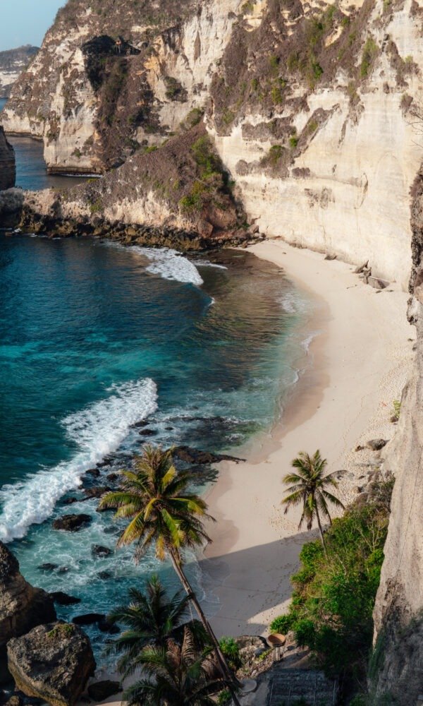 The ocean hitting the sandy beach surrounded by cliffs